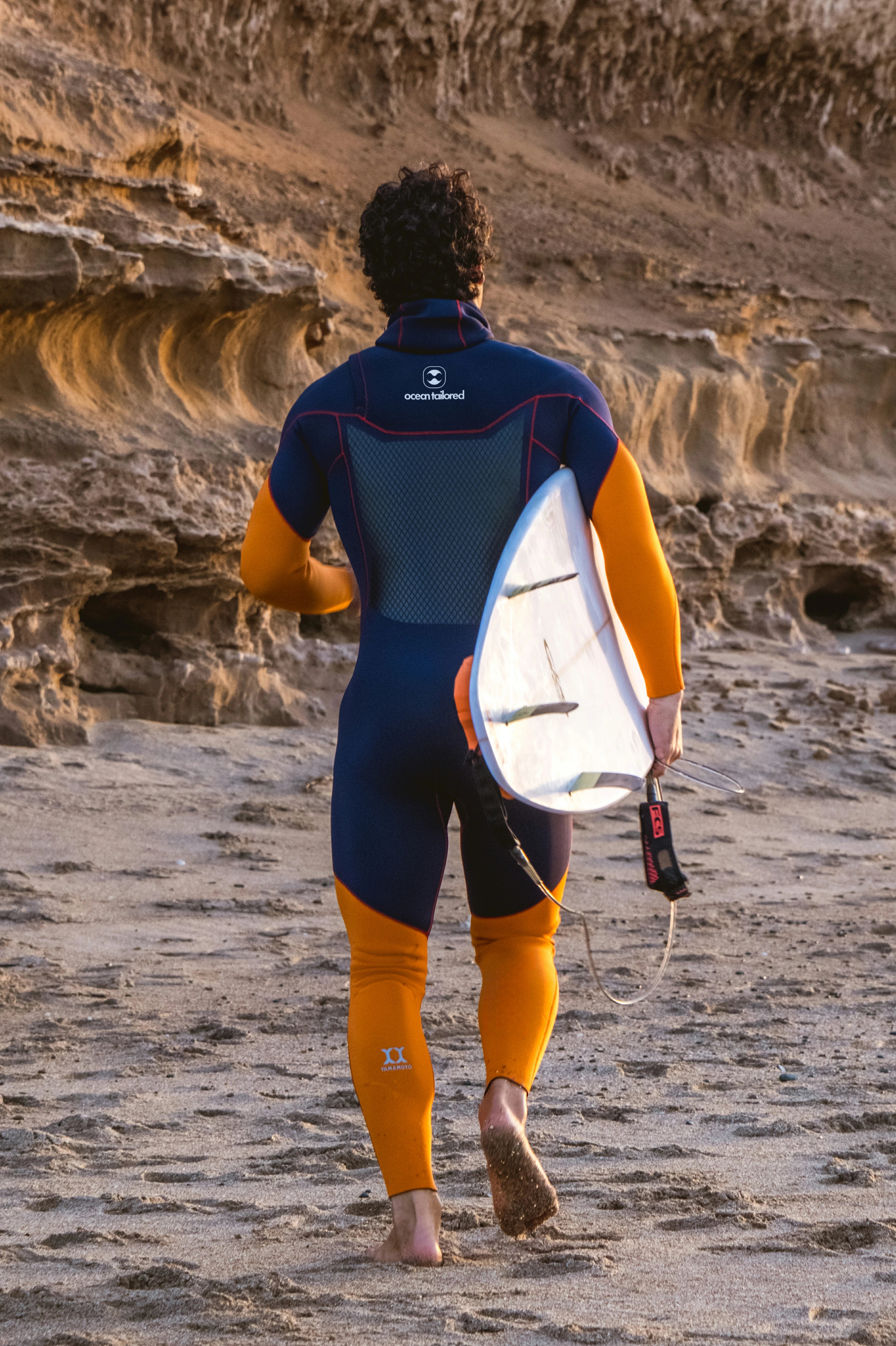 Men's Custom Slant Zip Curve Wetsuit with Surfing Board on beach