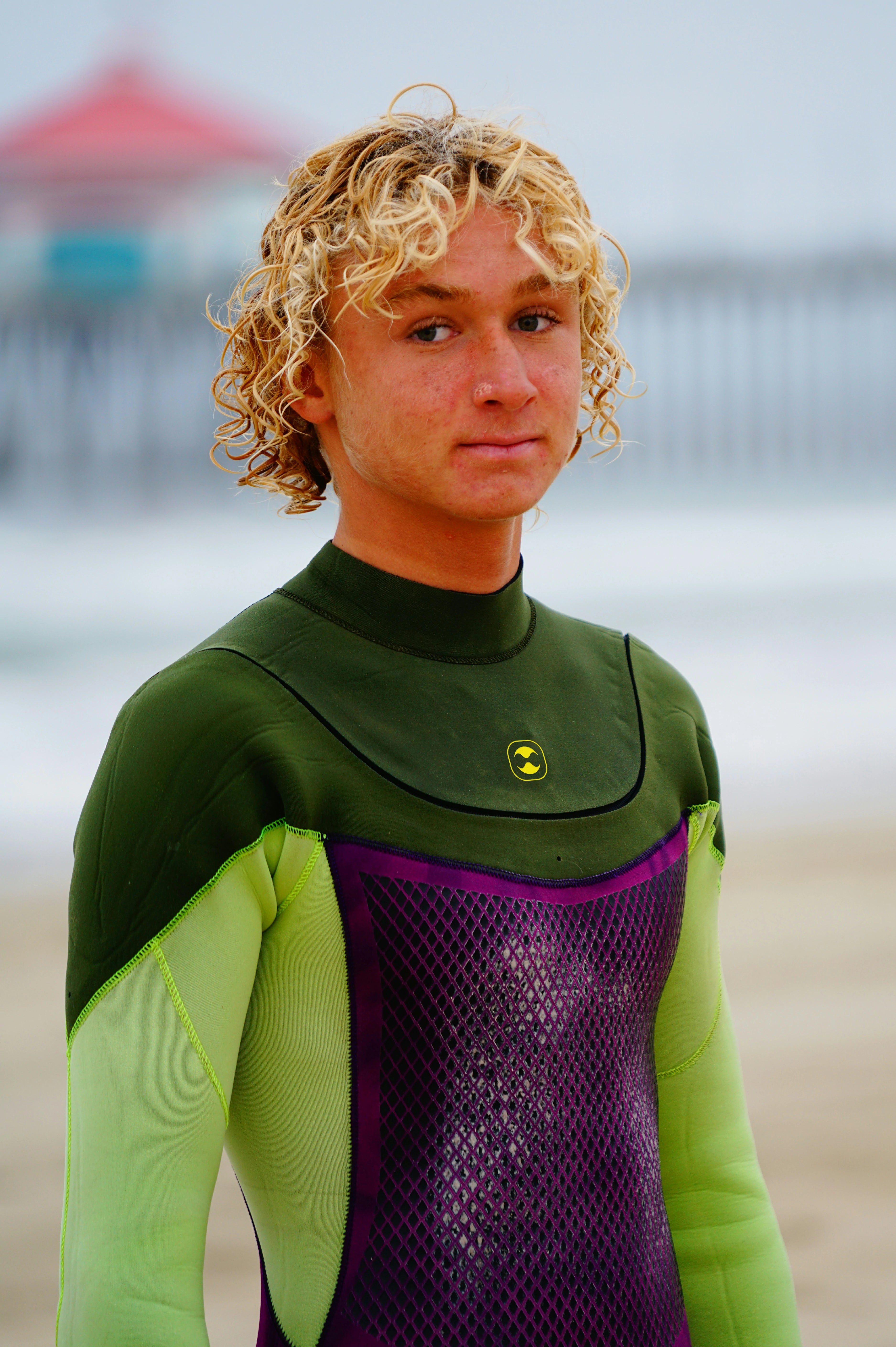 Person wearing a green and purple Flex U-Zip Wetsuit on a beach