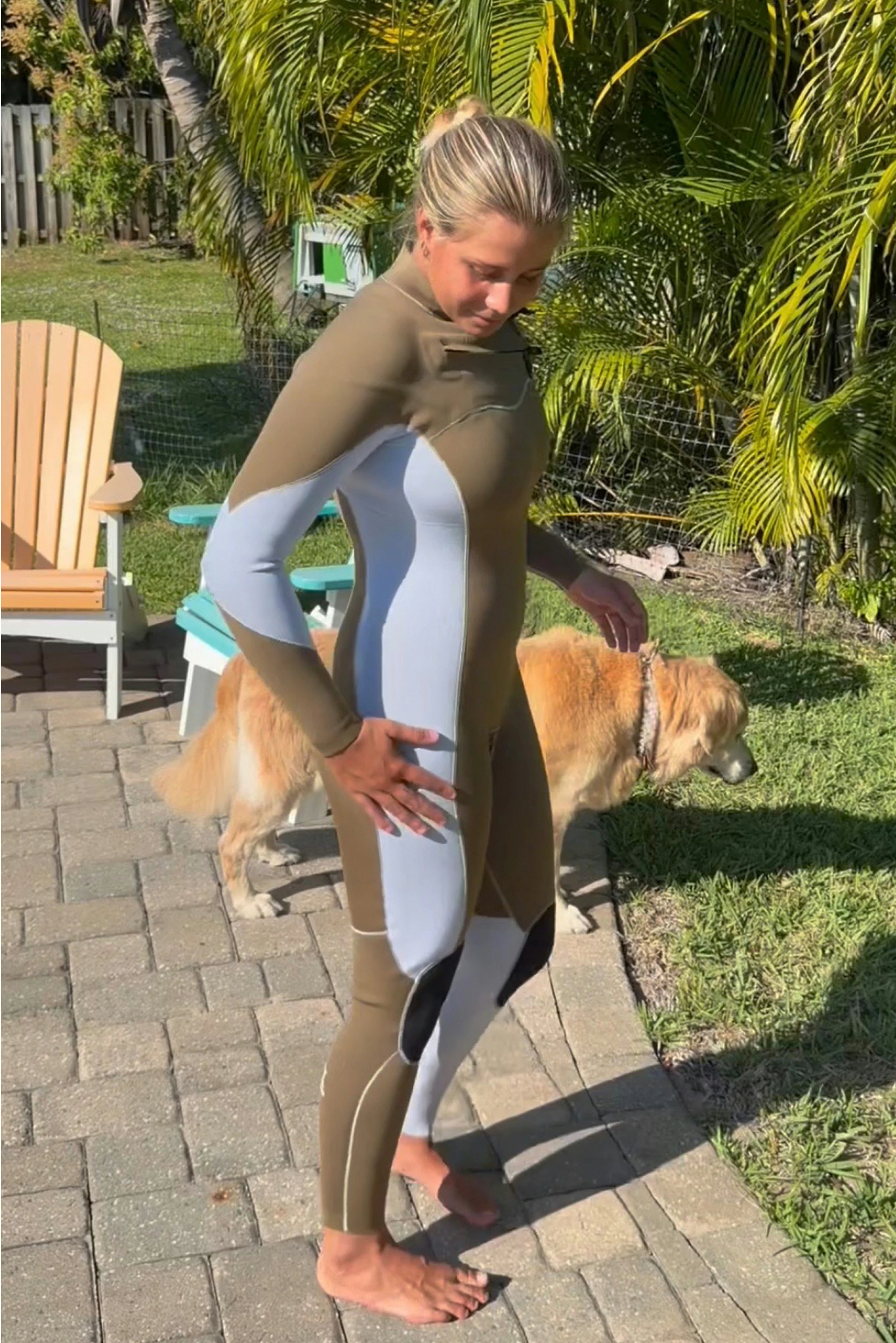 A woman wearing a custom slant zip unique bodysuit with a dog in a backyard setting